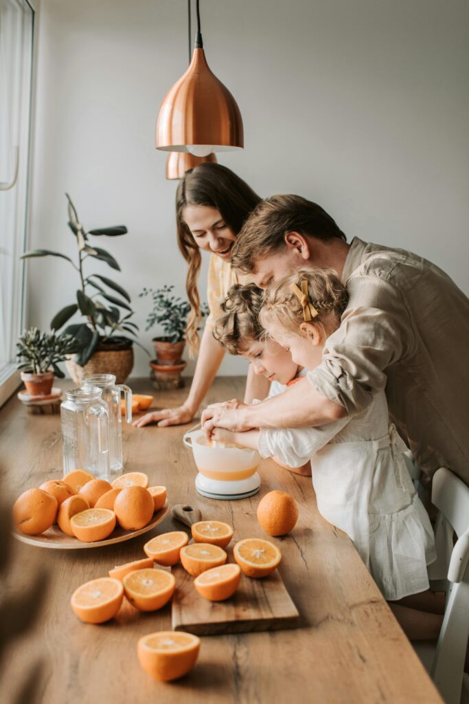 A family enjoys squeezing fresh orange juice together in a cozy kitchen setting filled with natural light.